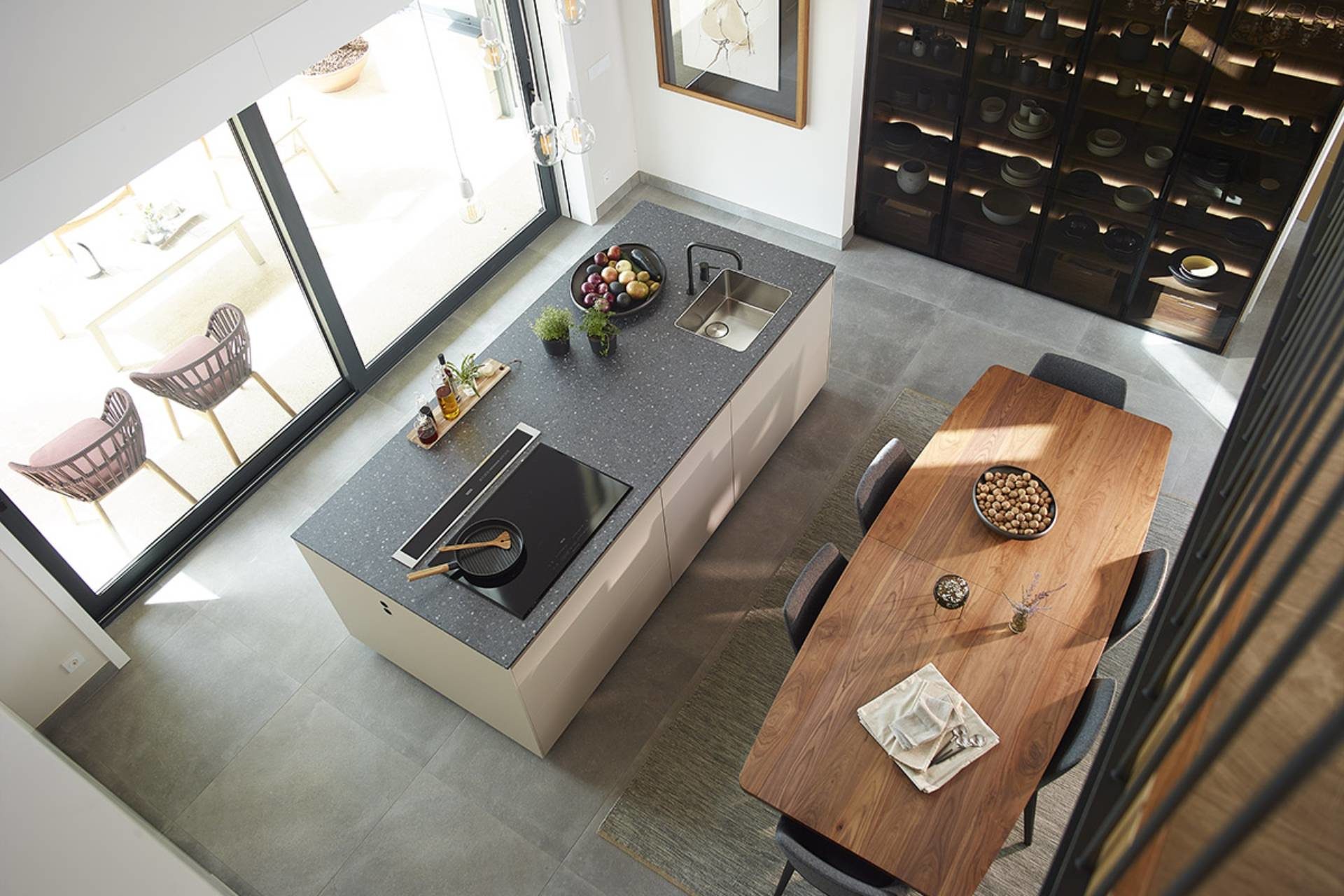 Overhead view of a kitchen with a central island, a smoked glass cabinet and a dining table
