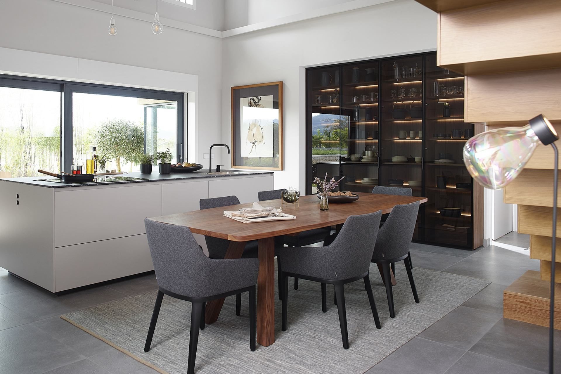Photo of kitchen with central island, smoked glass display cabinet and dining table