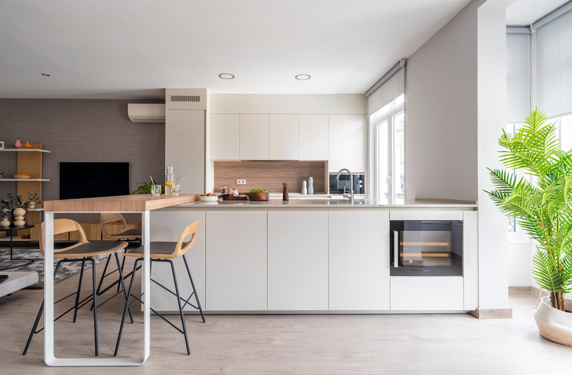 Open-plan white peninsula kitchen with perpendicular oak breakfast bar extension