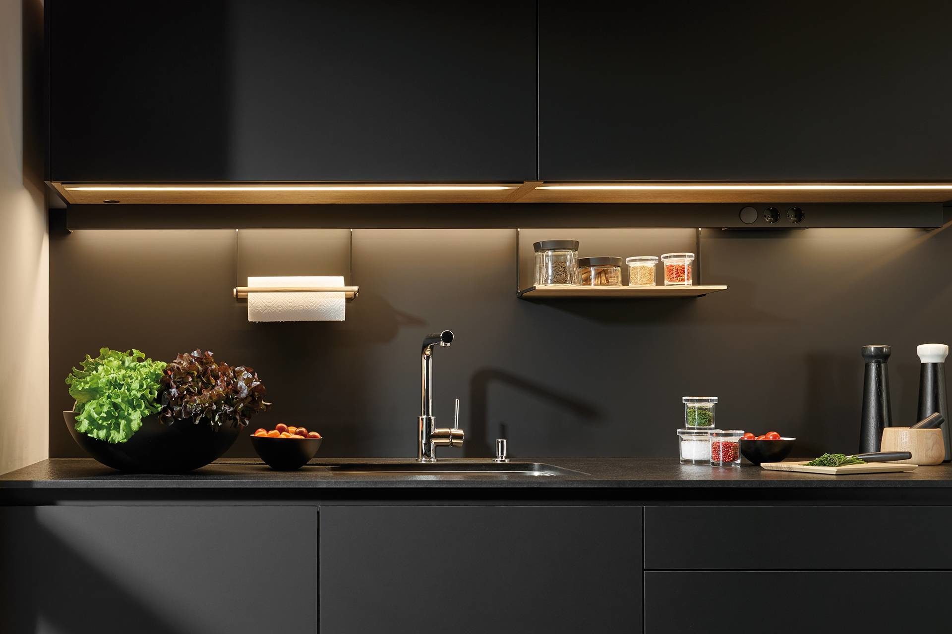 Photo of lighting profiles installed on a black worktop in a dark kitchen designed by Santos