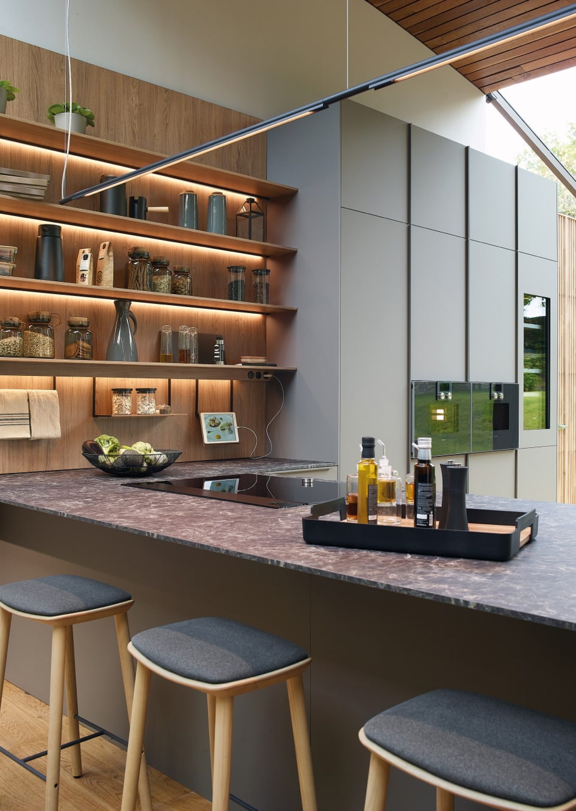 Grey and wood kitchen, with lighted shelving unit and peninsula with a raised bar