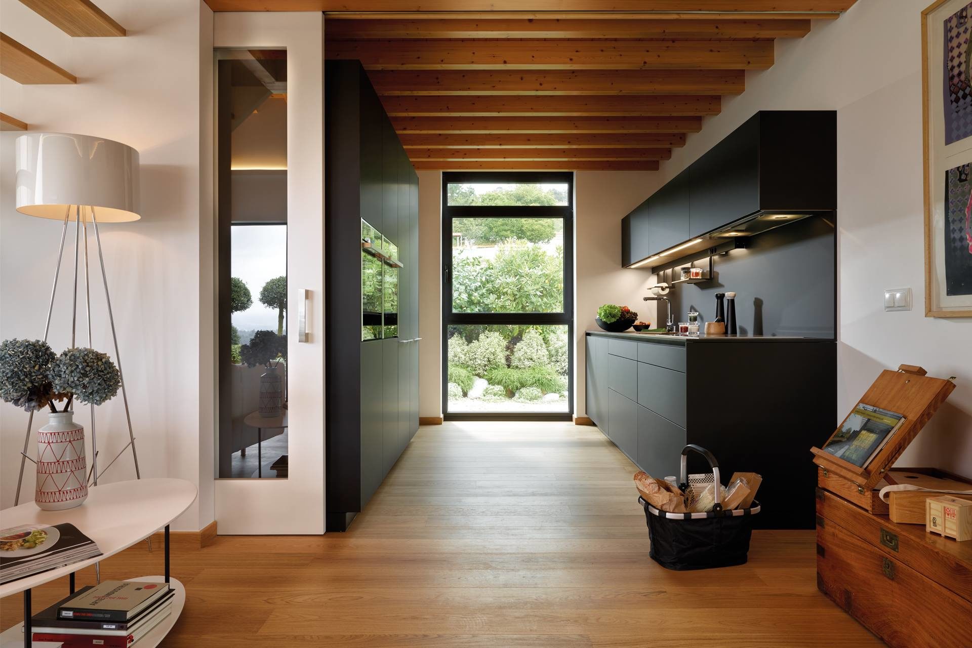 Photo of black kitchen integrated in an interior with wood on the ceiling and floor 