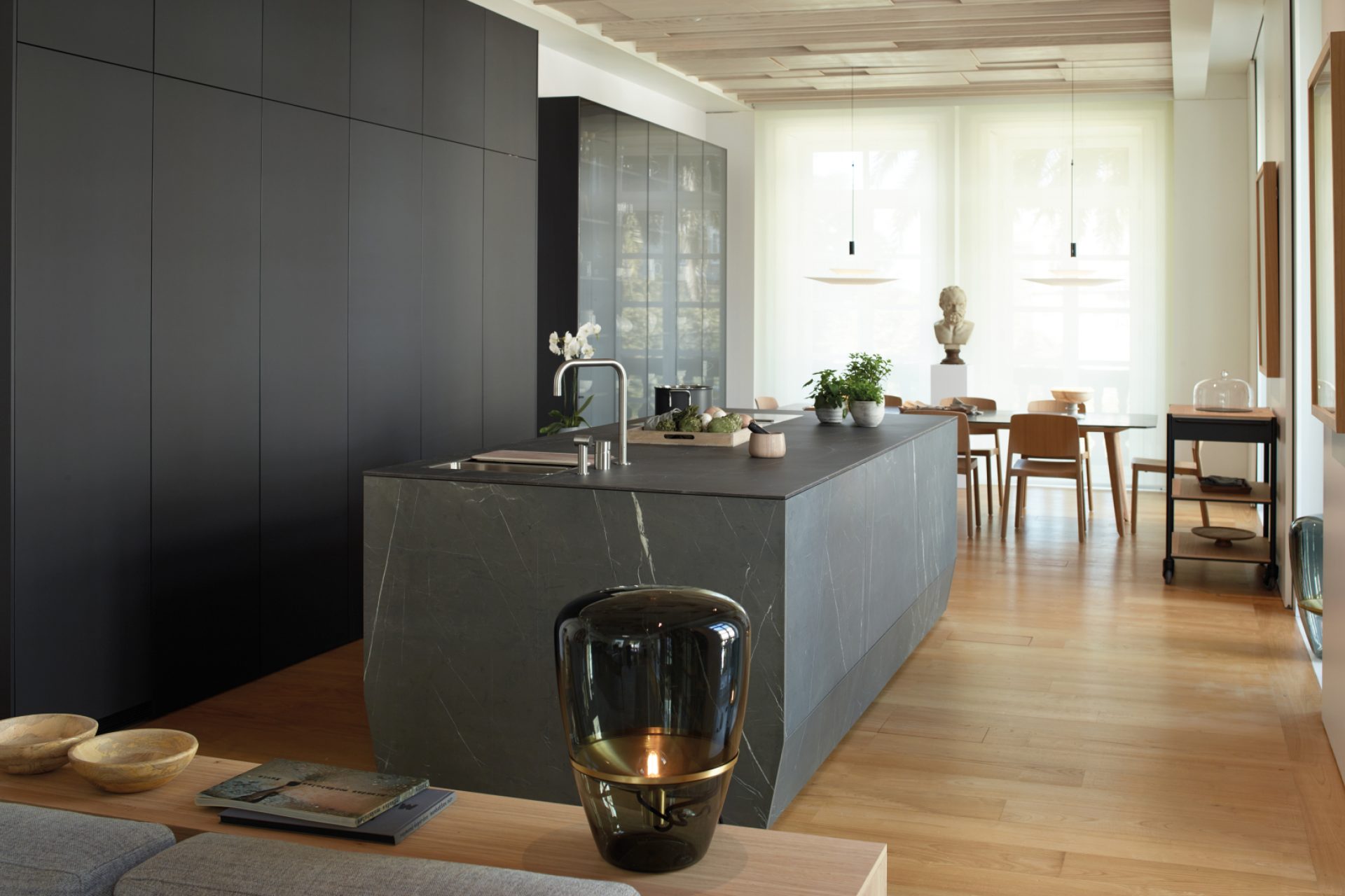 Dark grey linear kitchen design with a central island, sideboard and display cabinet, open to the dining room and the living room