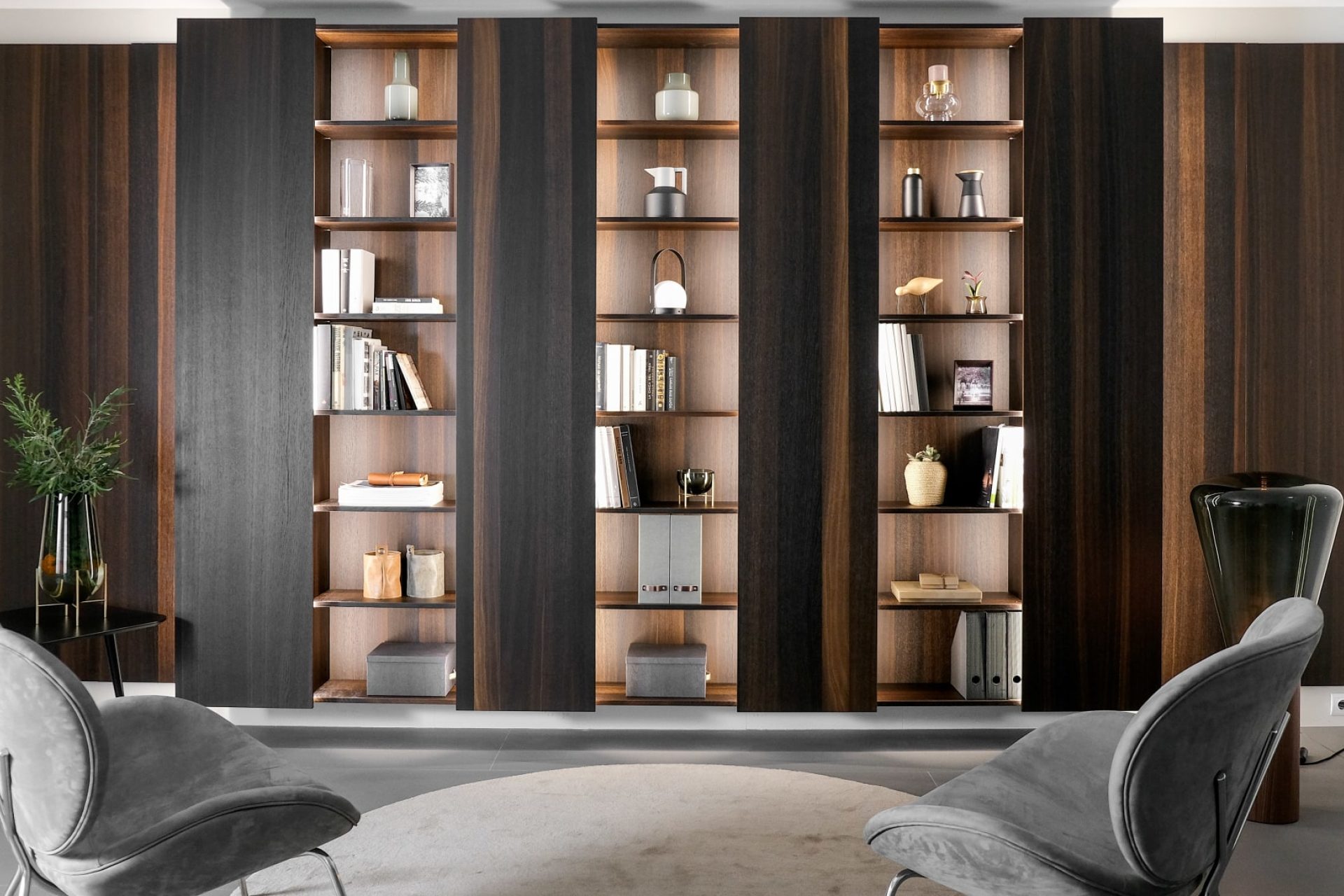 Living room display comprised of a Santos bookcase in natural oak veneer, two grey canvas armchairs by Amura