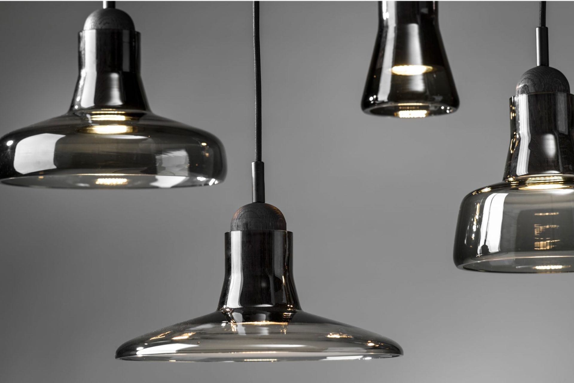 Four pendant smoked-glass lamps, each shaped differently