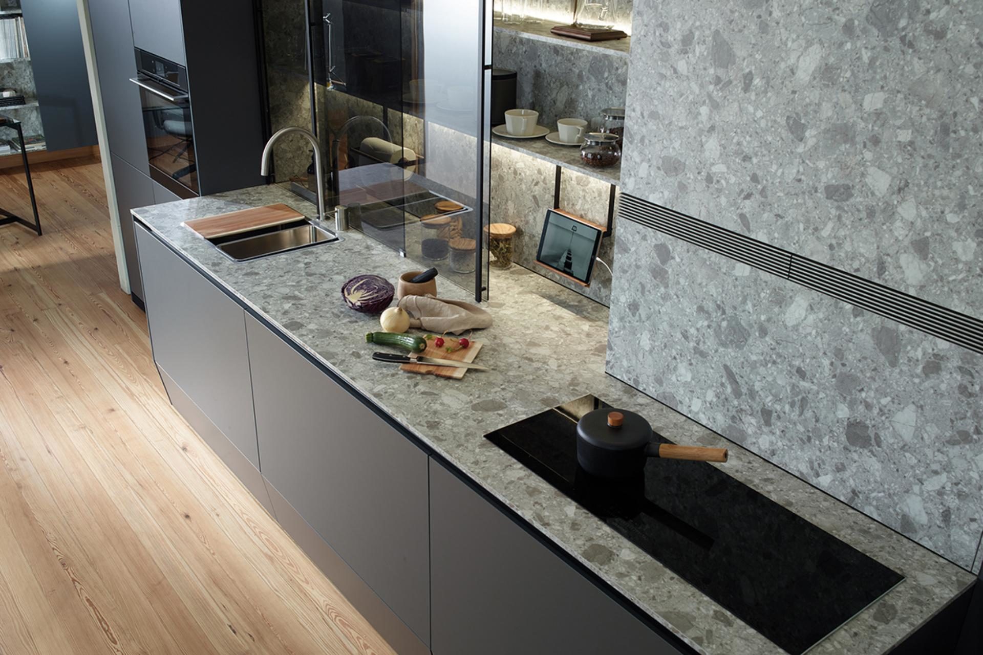 Kitchen units with black front and grey marble credence and worktop