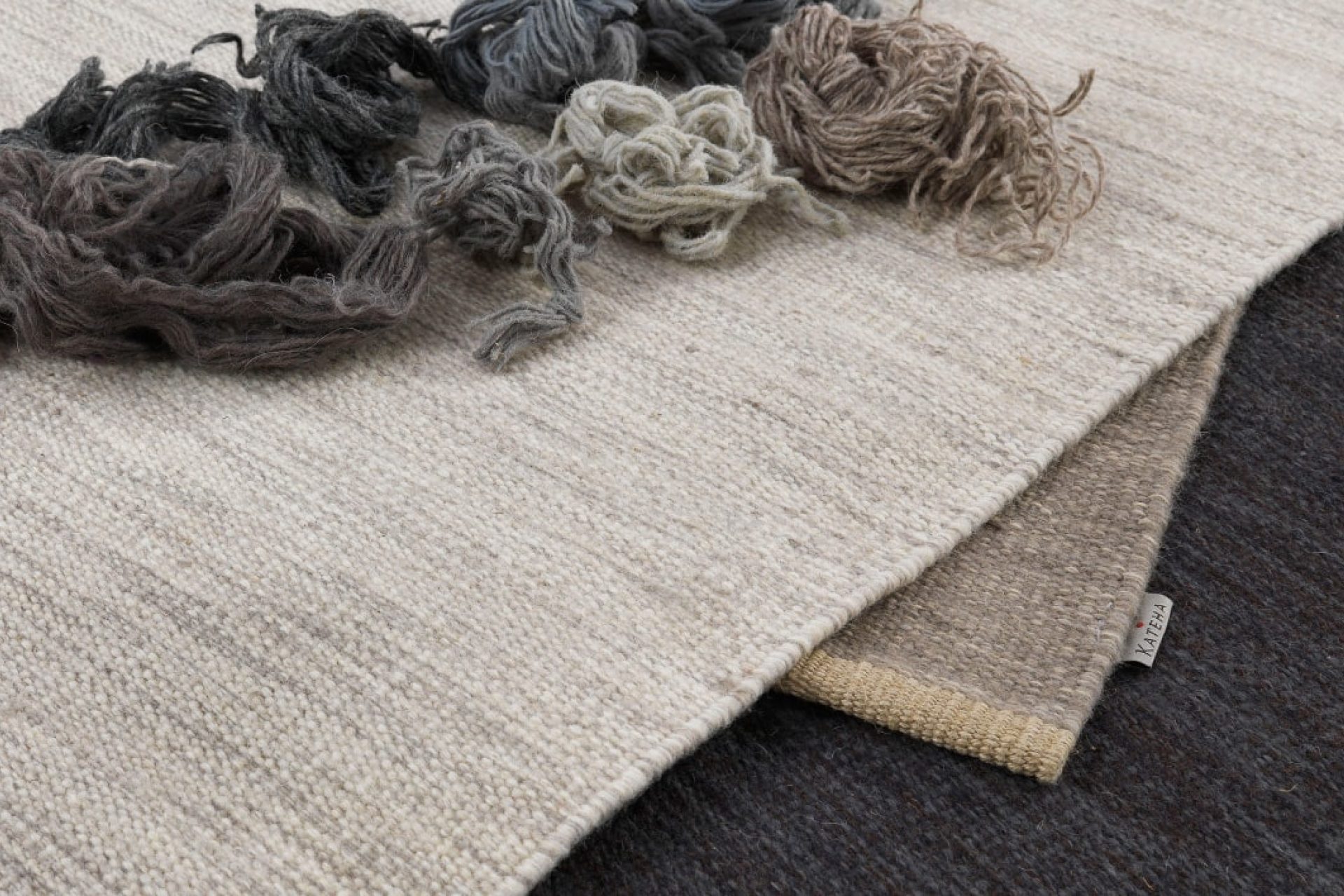Display showing three parts of the woollen designer rugs, with grey and beige woollen yarn pieces