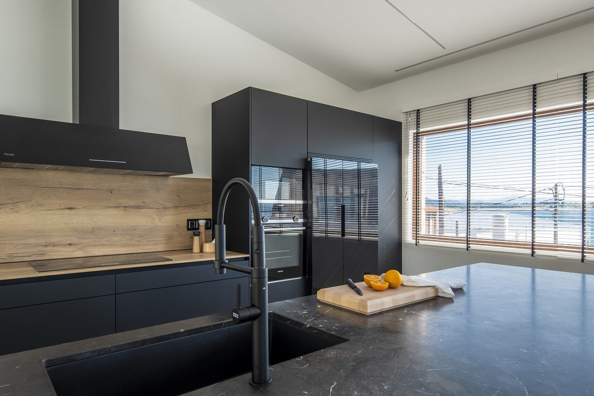 Proyecto de cocina negro mate con detalles en acabado madera clara de roble y electrodomésticos negros integrados