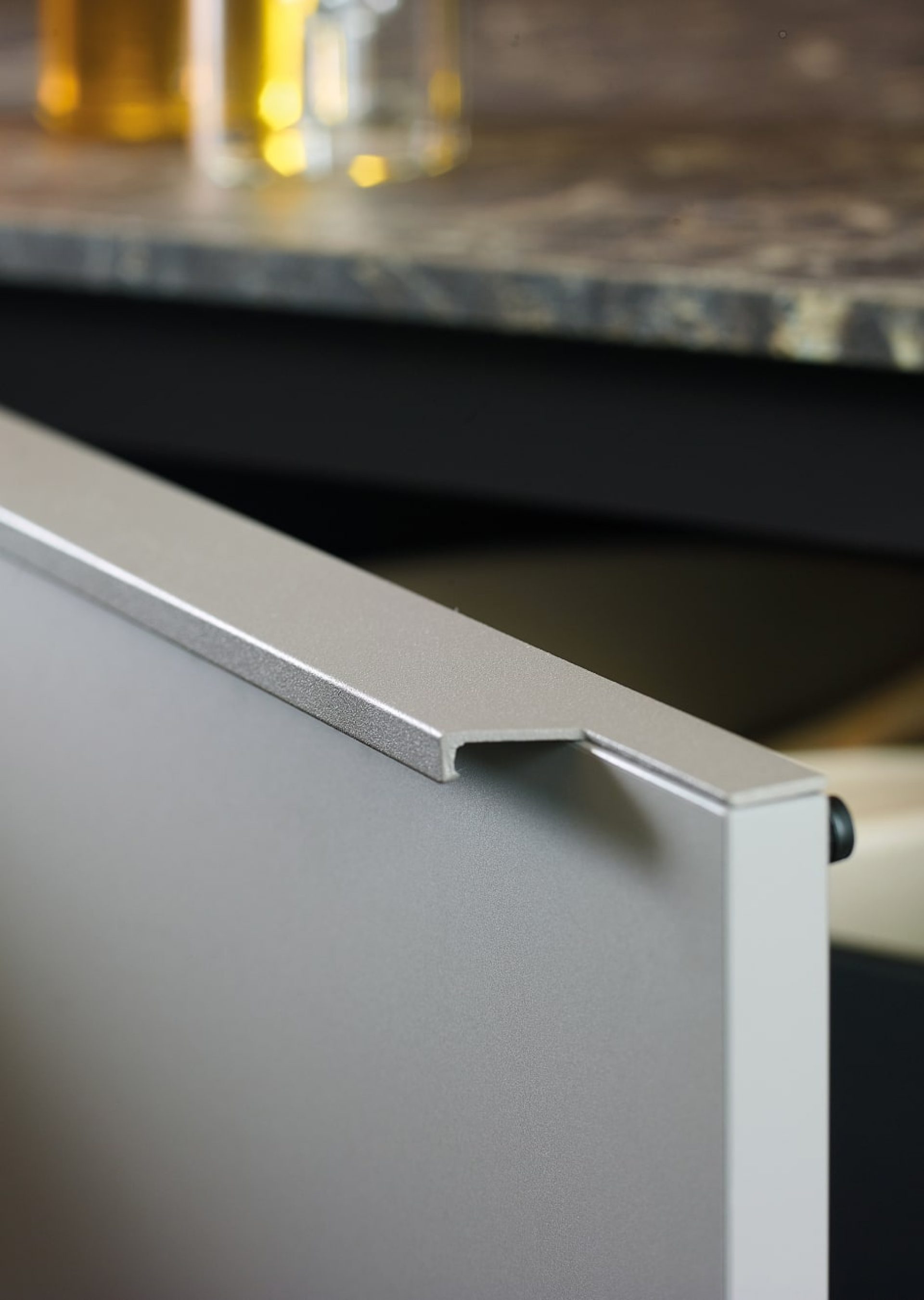 Mueble de cocina gris visón con tiradores integrados y encimera de laminado efecto mármol