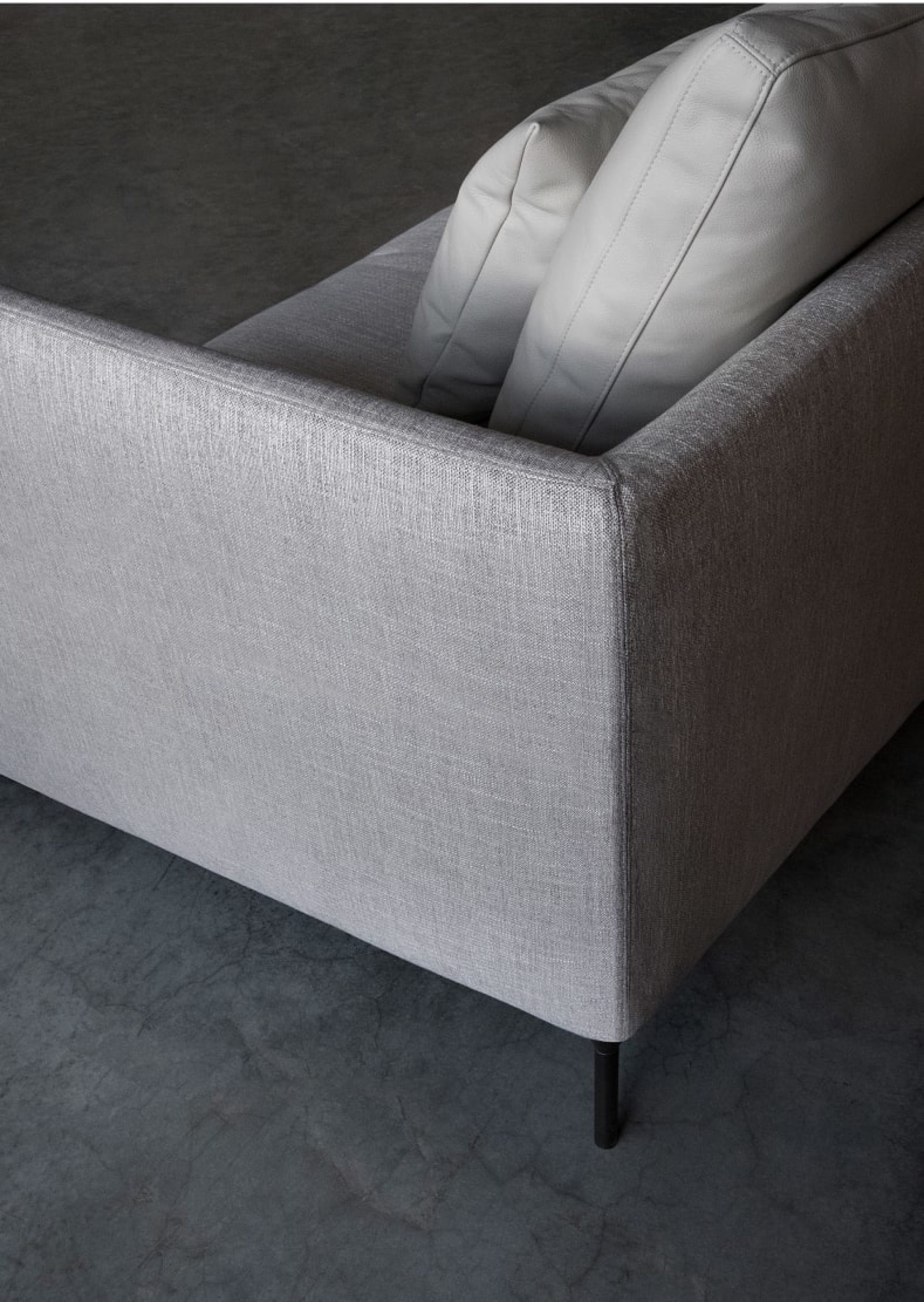 Sofá de tejido gris con respaldo rectangular y estructura ligera de acero negro, de la marca italiana Bensen