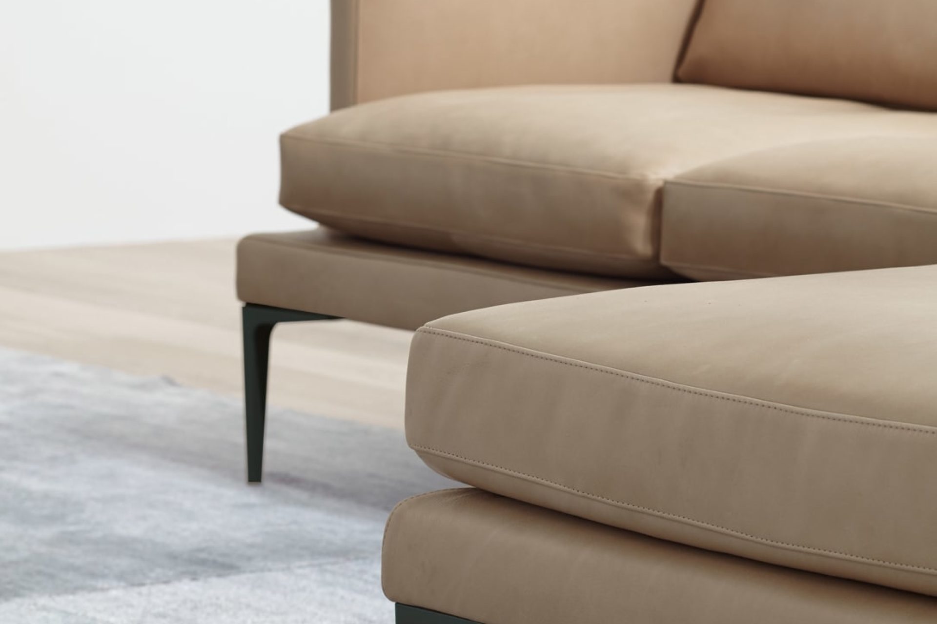 Sofá de diseño en piel beige con patas de acero elegido por eba para sus proyectos de interiorismo