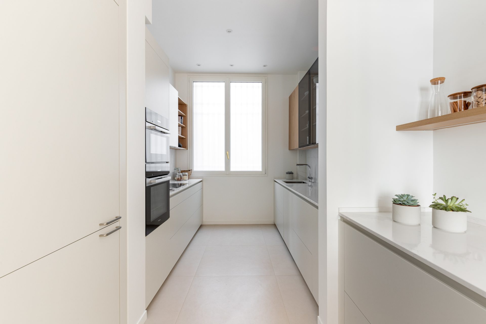 Petite cuisine blanche et bois implantée en parallèle aux lignes minimalistes