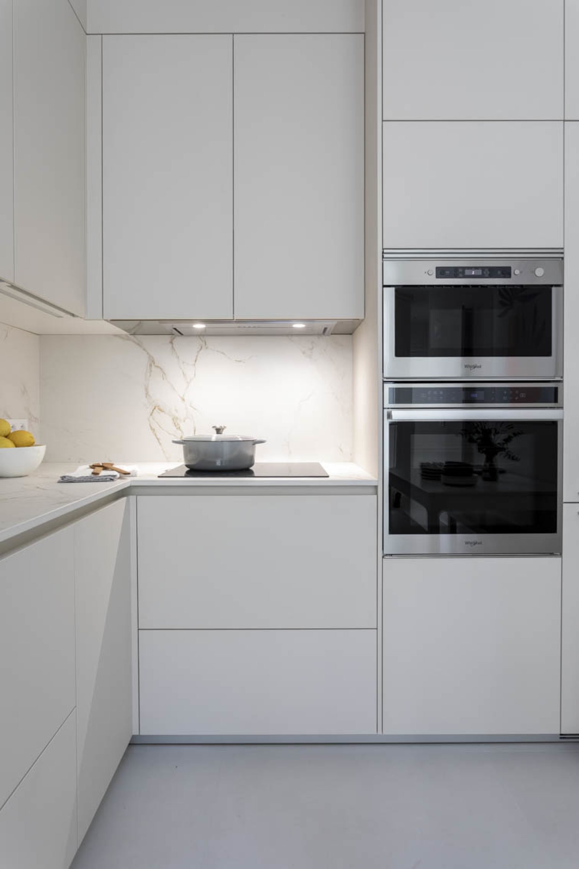 Cuisine fermée dans un appartement parisien coloris Blanc Perle Soie et plan de travail en Dekton