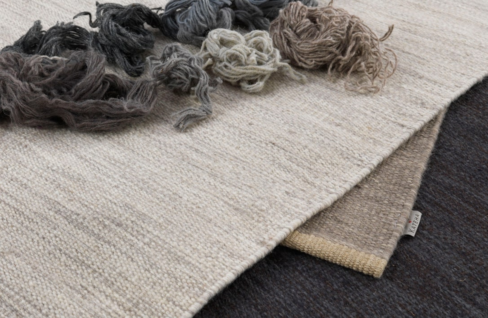 Aperçu de trois parties de tapis en laine design, avec des morceaux de fils de laine dans des tons de gris et de beige