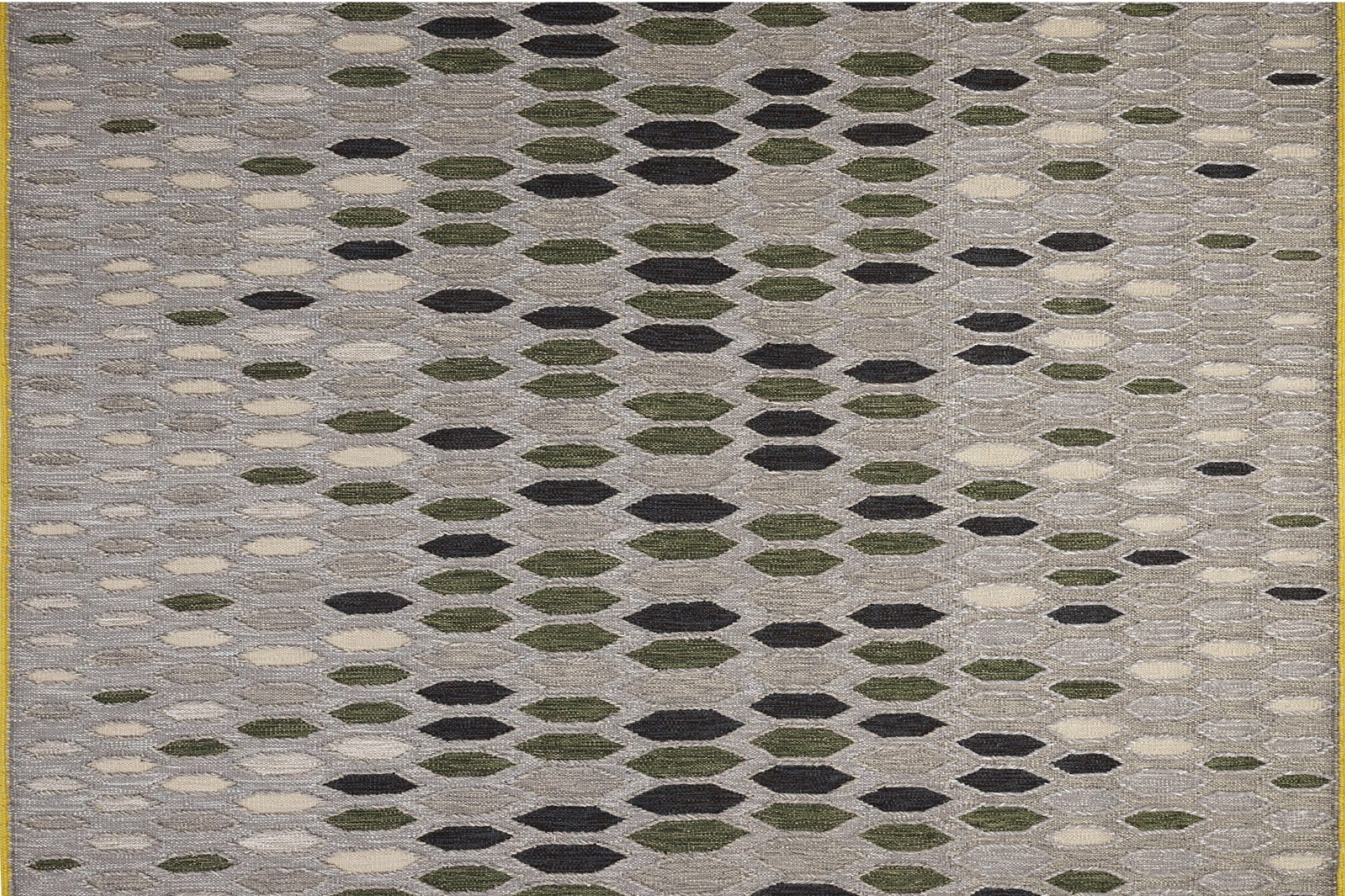 Vue sur une partie de tapis avec des losange de tons beige, vert et gris
